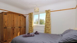 A bedroom with a bed, a wardrobe, and a window with curtains. - Cedar View (Norwich)