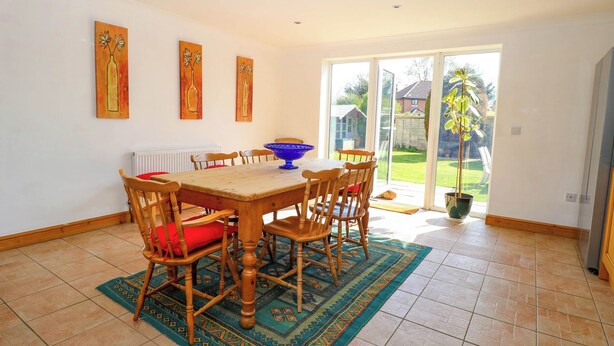 A dining area with a wooden table and chairs, a blue bowl, and a patterned rug. - Cedar View (Norwich)