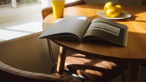 Een tafel met een boek, een gele beker en een bord met citroenen.