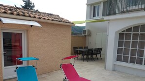 Une terrasse avec deux fauteuils, une table et des chaises.