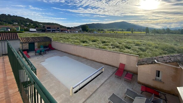 Une terrasse sur le toit dotée d’une grande surface plane, d’une rambarde en métal et de quelques chaises et tables.