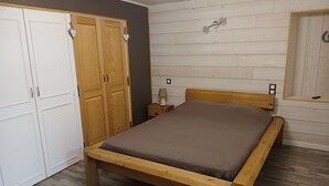 Une chambre à coucher avec un lit en bois, une armoire et une table de chevet.