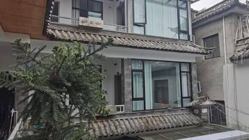 Un edificio de dos plantas con balcón, ventanas amplias y un techo de tejas tradicionales.