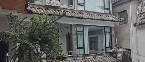 A two-story building with a balcony, large windows, and a traditional tiled roof.