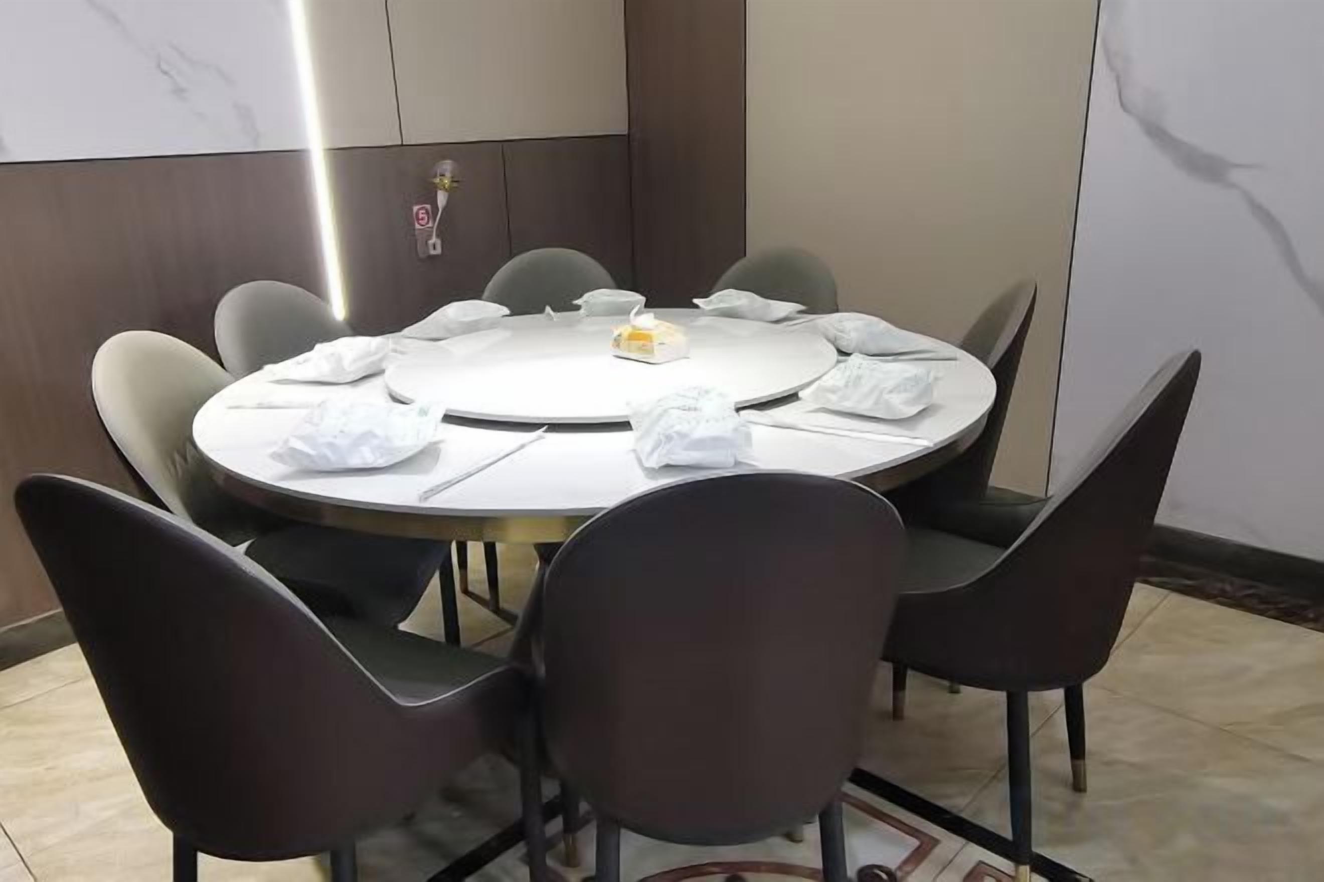 Una mesa redonda con ocho sillas, un mantel blanco y un pequeño centro de mesa.