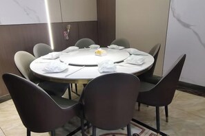 A round table with eight chairs, a white tablecloth, and a small centerpiece. - Dali Yuji Courtyard (Dali City)