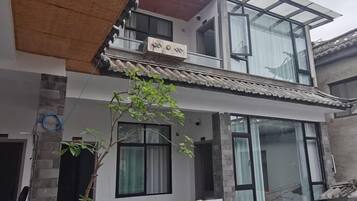 Un edificio de dos plantas con balcón, ventanas amplias y techo tradicional.