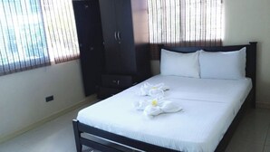 Una cama bien tendida con sábanas y toallas blancas dispuestas de forma decorativa.