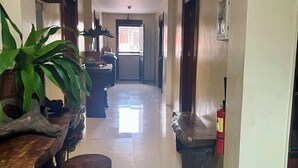 Un pasillo con piso pulido, muebles de madera, un extintor y una puerta que da a una habitación.