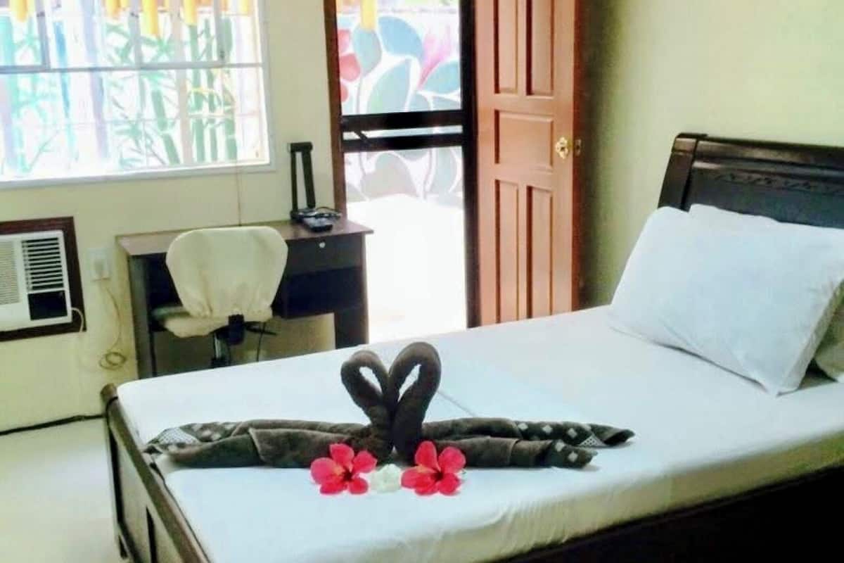 A hotel room with a bed, a desk, and a chair.