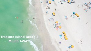 Een strand met vele parasols en mensen, met de tekst 'Treasure Island Beach' en de vermelding '8 mijl verderop'.