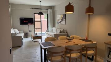 A modern living room with a sofa, a coffee table, and a TV mounted on the wall.