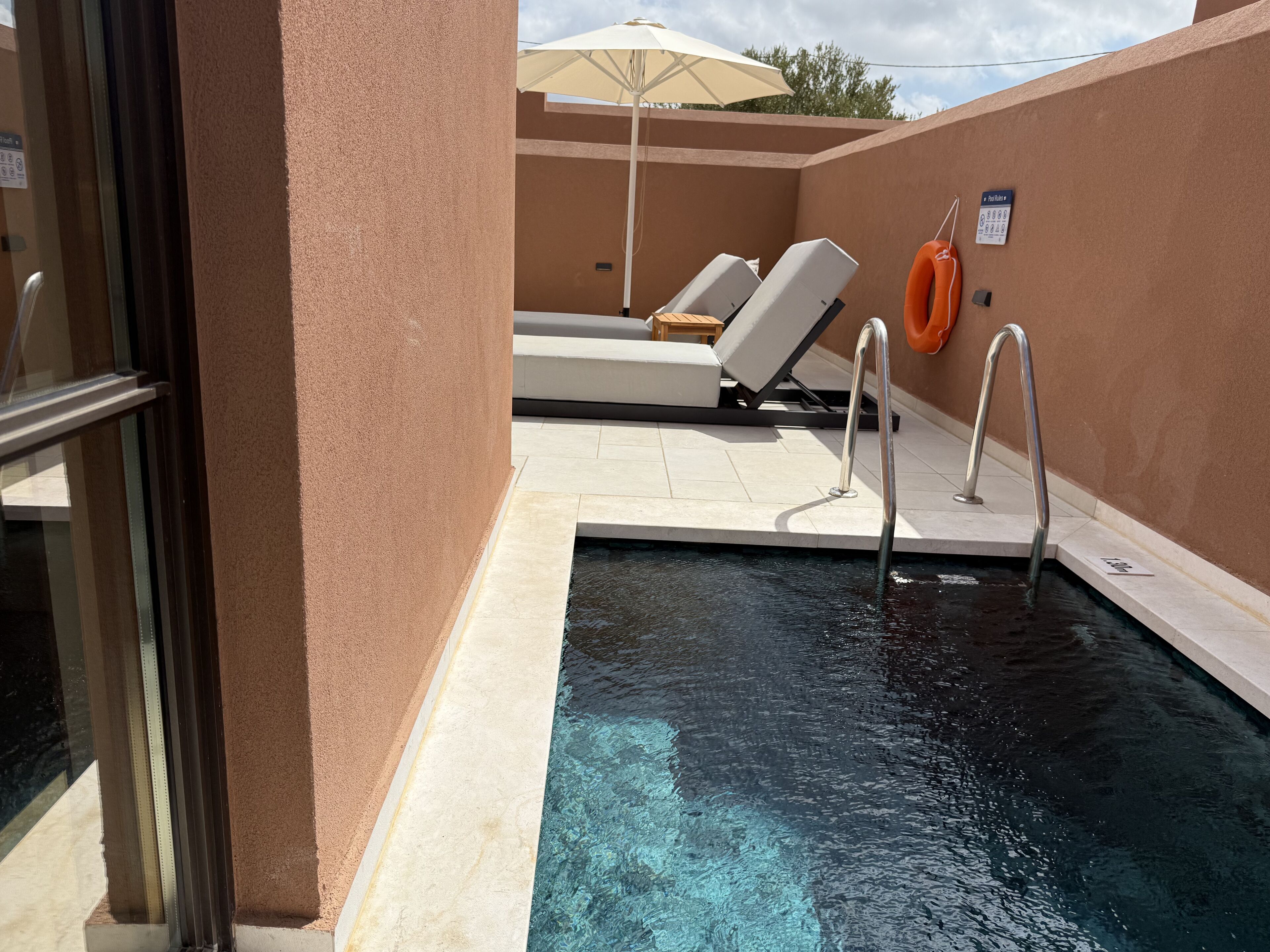 Un área de piscina con sillas de descanso y un flotador salvavidas.
