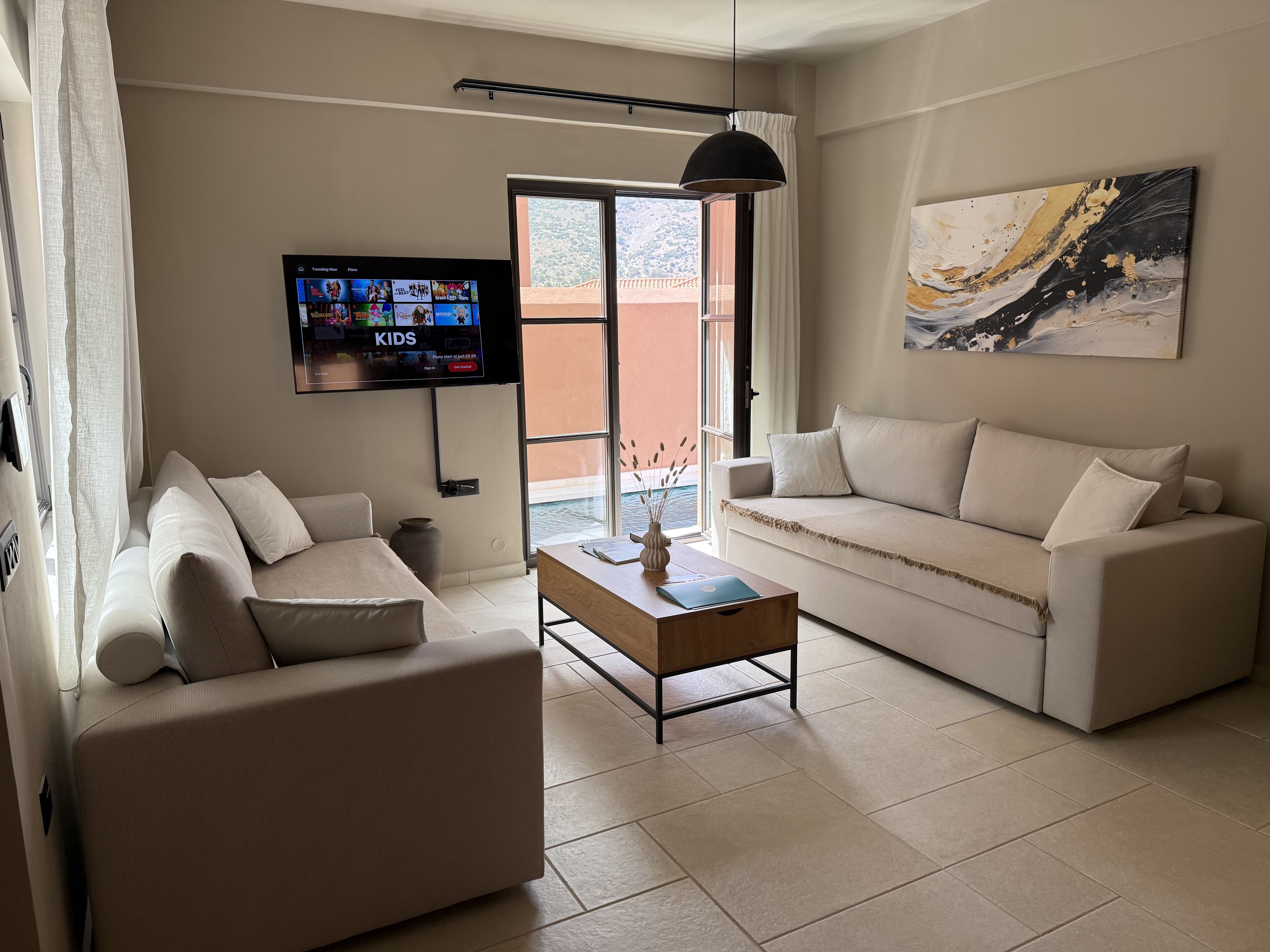 A living room with two sofas, a coffee table, a TV mounted on the wall, and a painting on the wall.