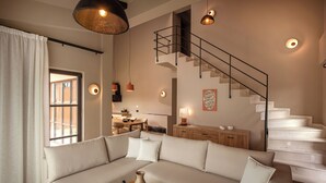 Ein modernes Wohnzimmer mit einer Eckcouch, einem Holztisch, einer Treppe und Pendelleuchten.