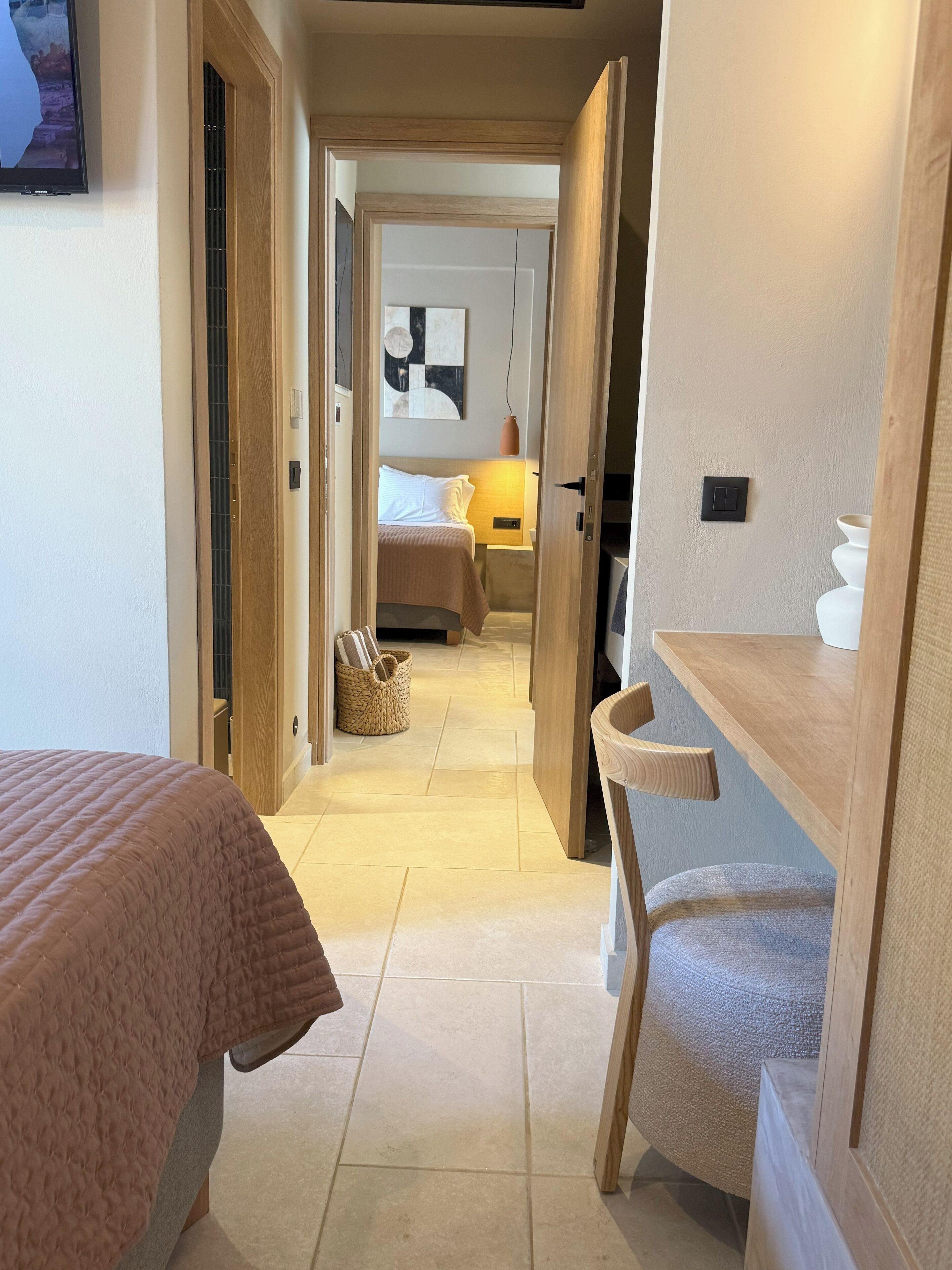 Een hotelkamer met een bed, een stoel, een nachtkastje, een lamp en een aan de muur bevestigde televisie.