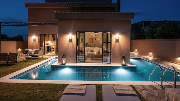 Ein modernes Haus mit Swimmingpool, Sitzgelegenheit im Freien und einer Glastür, die zu einem Wohnbereich führt.