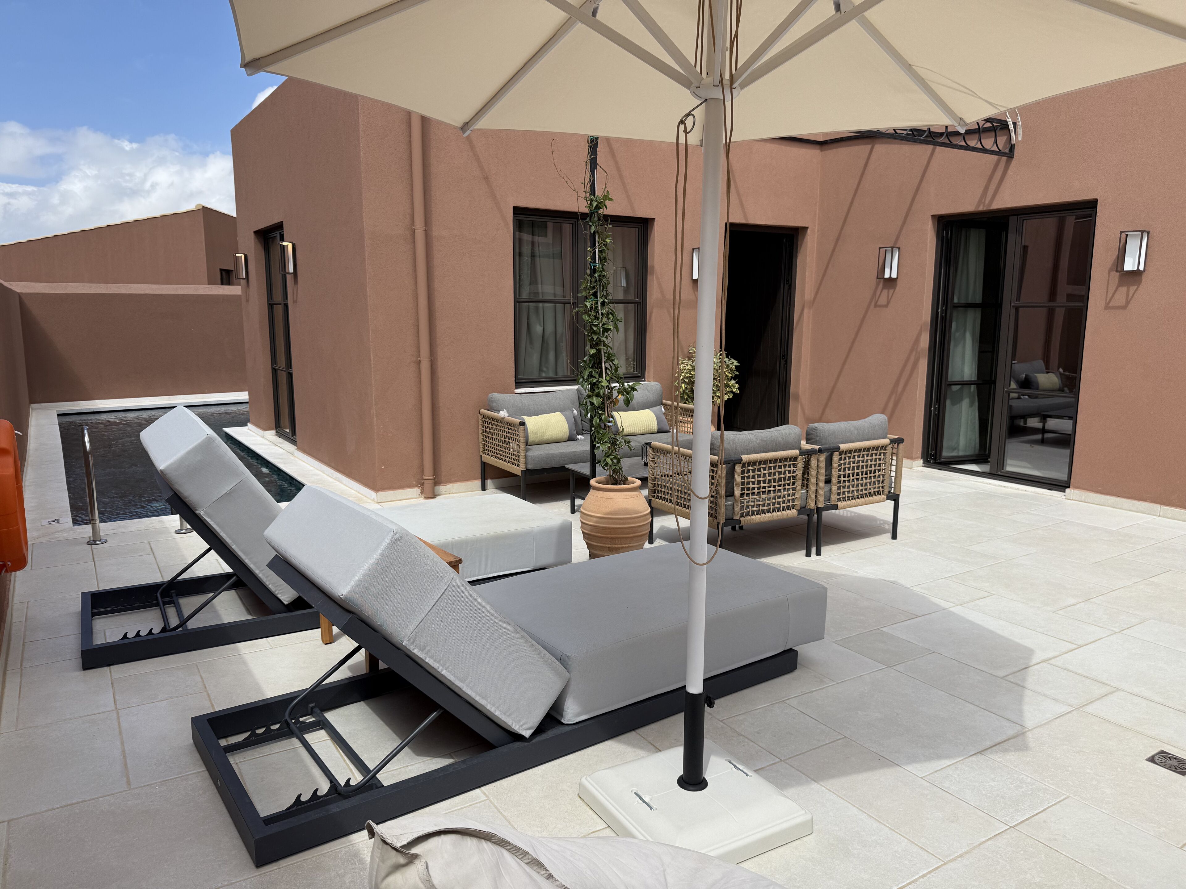 A rooftop terrace with sun loungers, a table, and a large umbrella.
