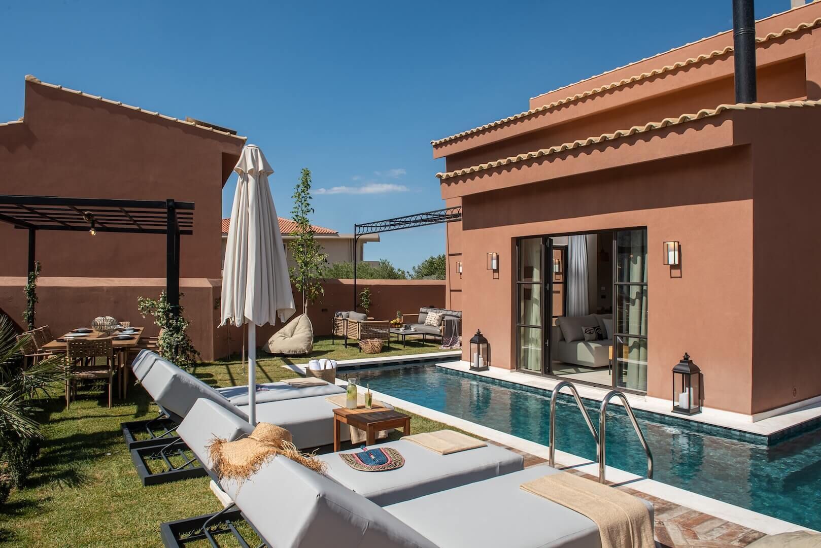 A poolside area with lounge chairs, a table, and umbrellas.