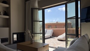 Ein modernes Zimmer mit einer großen Glasschiebetür, die zu einer Außenpatio führt. Im Inneren befindet sich ein Couchtisch aus Holz, eine Couch und ein Fernseher auf einem Schrank.