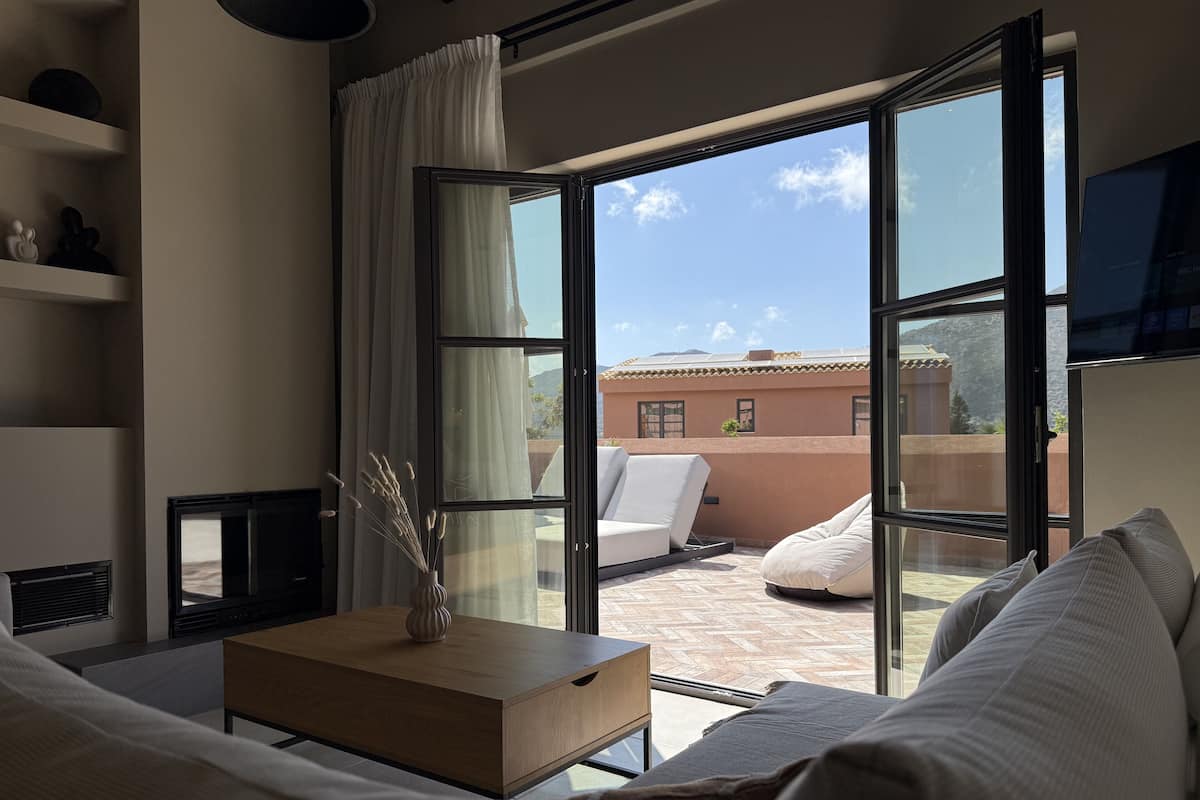 A modern room with a large sliding glass door leading to an outdoor patio. Inside, there is a wooden coffee table, a sofa, and a television on a stand.