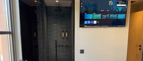 A hotel room with a large flat-screen TV mounted on the wall displaying various channels and apps.