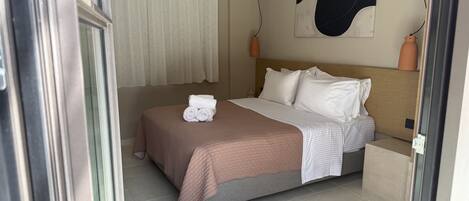 A hotel room with a bed, a large abstract painting on the wall, and a window with curtains.