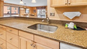 A kitchen with granite countertops, a stainless steel sink, wooden cabinets, and a window overlooking a balcony. - 3 Bedroom Condo at Key Condo in Keystone (Keystone)