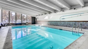 An indoor swimming pool with clear glass walls, a tiled floor, and a ceiling with exposed beams. - 3 Bedroom Condo at Key Condo in Keystone (Keystone)