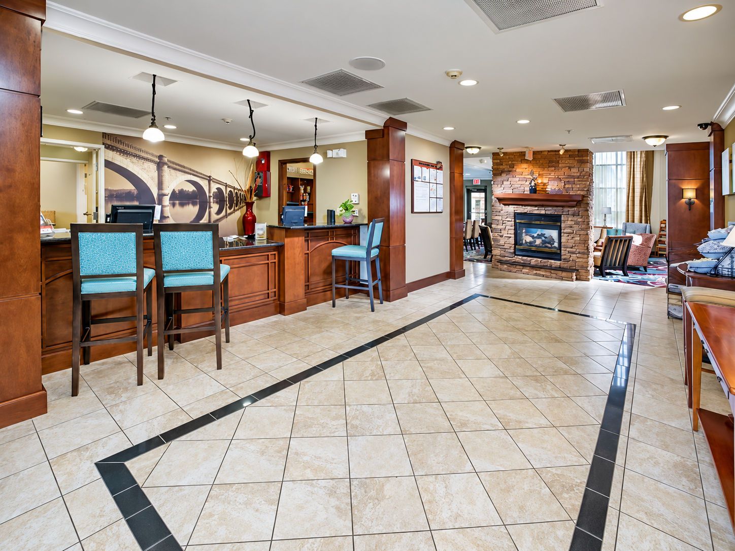 A hotel lobby with a reception desk, seating area, and a fireplace.