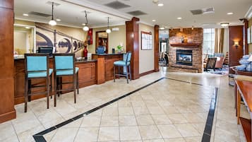 A hotel lobby with a reception desk, seating area, and a fireplace.