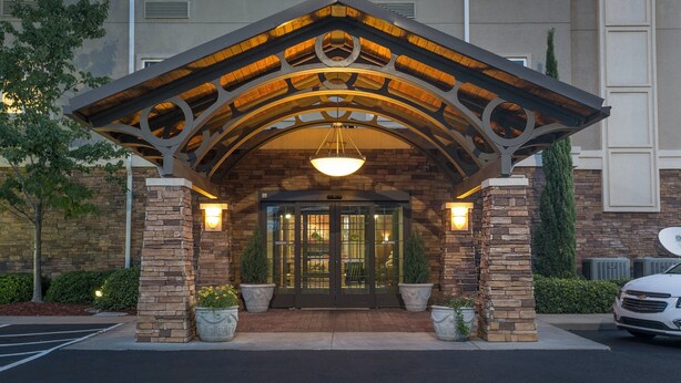 A hotel entrance with a stone facade, a wooden arch, and a hanging light fixture. - King Suite Near Bush Field Airport | Free Daily Breakfast (Augusta)