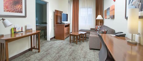 Una habitación de hotel con un escritorio de madera, un sofá, un televisor y una cama.
