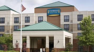 A Staybridge Suites hotel with a green roof, a flag, and a sign indicating the name.
