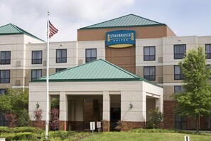 Un hôtel Staybridge Suites doté d’un toit végétalisé, d’un drapeau et d’une enseigne indiquant son nom.