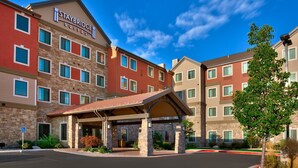 A Staybridge Suites hotel with a covered entrance, multiple floors, and a clear blue sky.