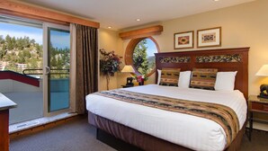 A hotel room with a large bed, a balcony with a glass door, and a view of a mountainous landscape. - Mountain View Villa with Pool + Hot Tub Access (Stateline)