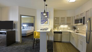 A hotel room with a bed, a desk, a chair, a small dining table, a sink, a microwave, a refrigerator, and a painting on the wall. - Free Breakfast. Gym. Near Medical Center. (Little Rock)