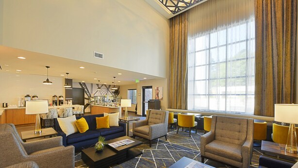 A spacious lobby with a modern design, featuring a mix of seating areas, a bar, and a kitchen in the background. - Free Breakfast. Gym. Near Medical Center. (Little Rock)