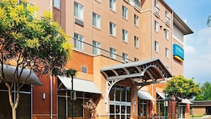 Un hôtel doté d’une entrée abritée, de nombreuses fenêtres et d’un espace extérieur aménagé pour s’asseoir.