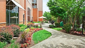 Un bâtiment en briques doté de grandes fenêtres et d’un chemin piétonnier dallé agrémenté de verdure.