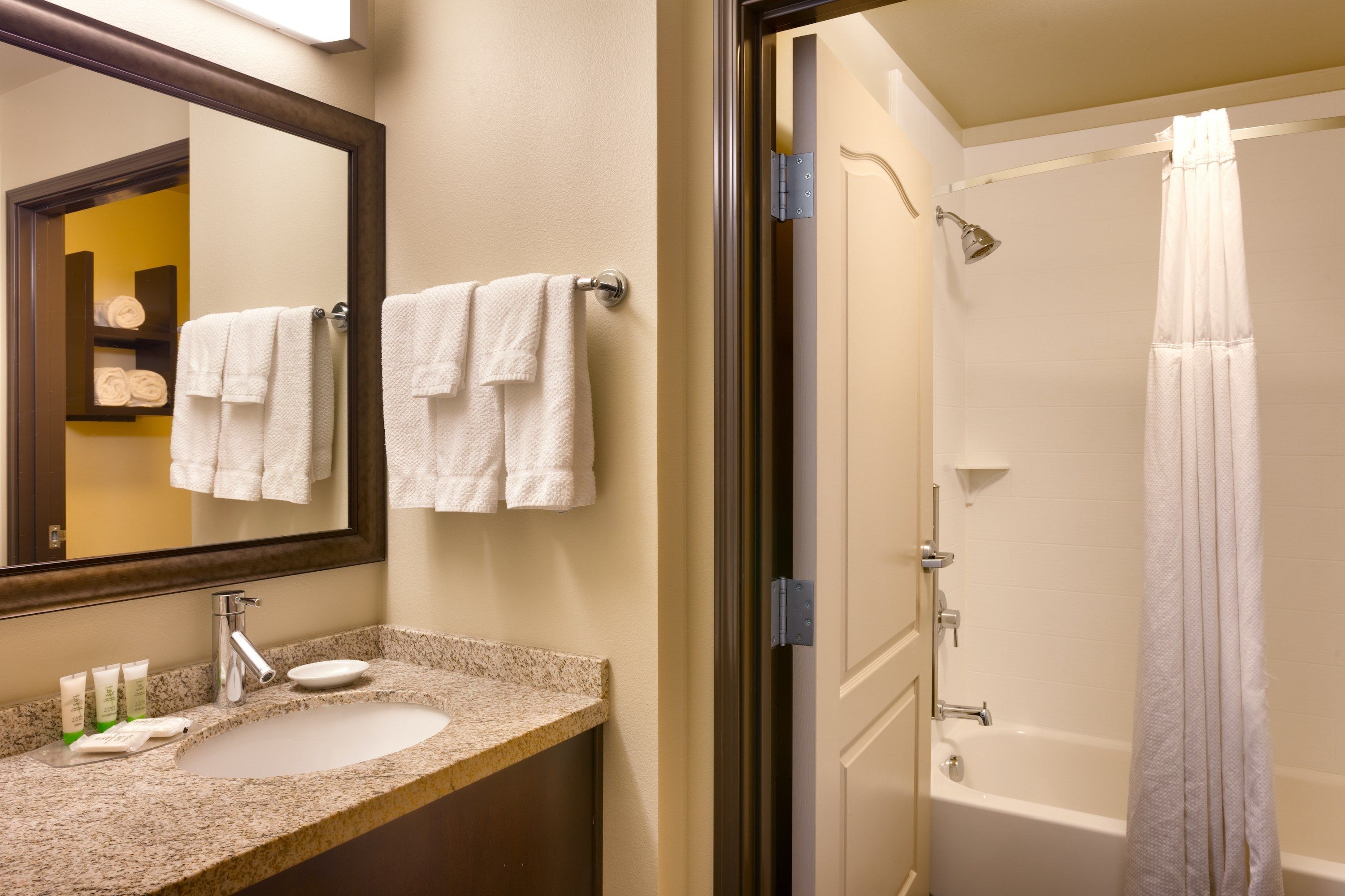 A bathroom with a sink, mirror, and shower.