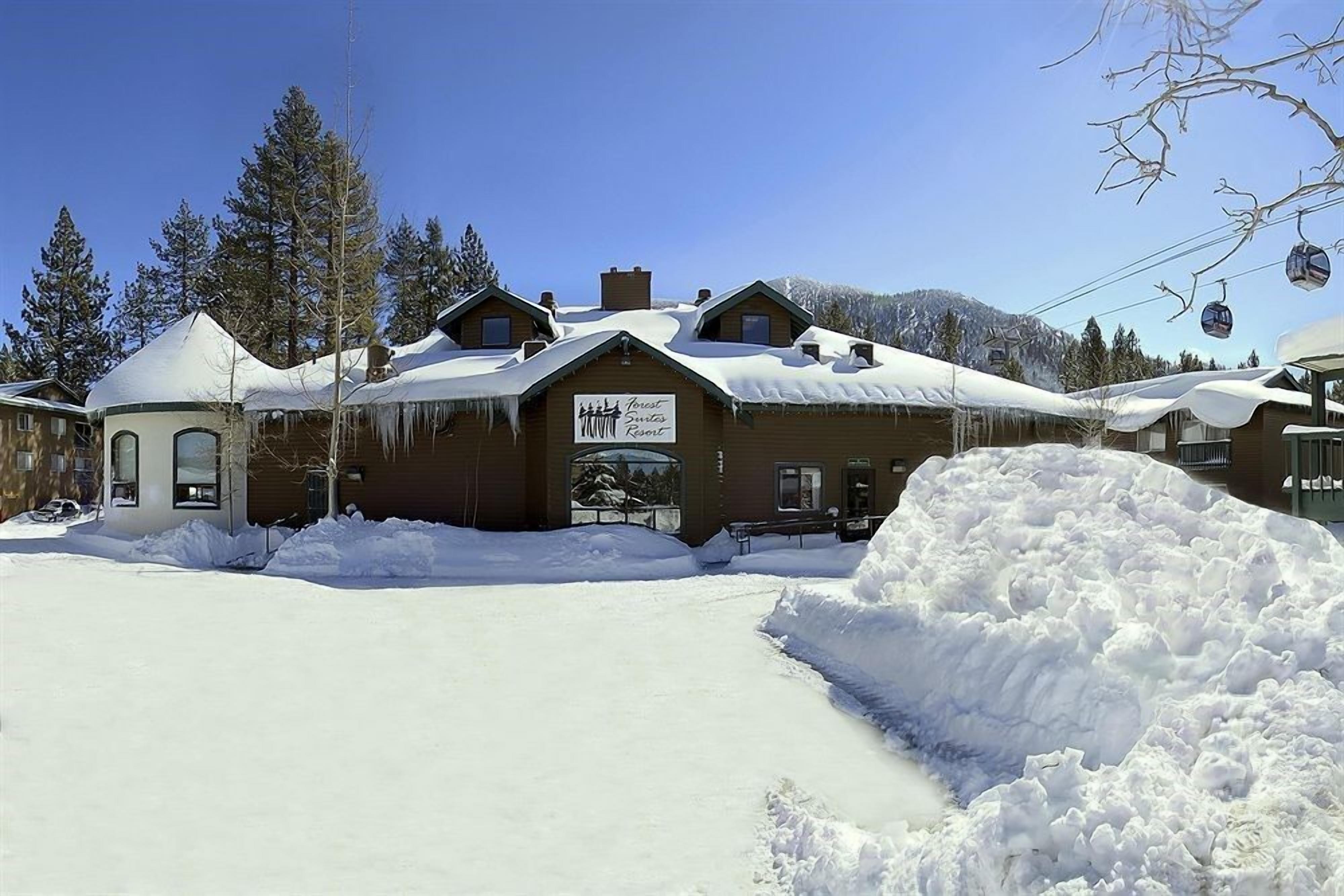 A lodge with a sign reading "Lodge", surrounded by snow-covered ground and trees, with a clear sky.