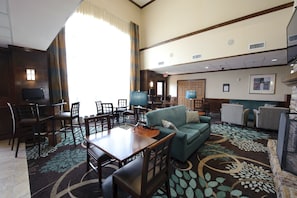 Un hall d’hôtel comprenant un espace repas, un canapé et un téléviseur.