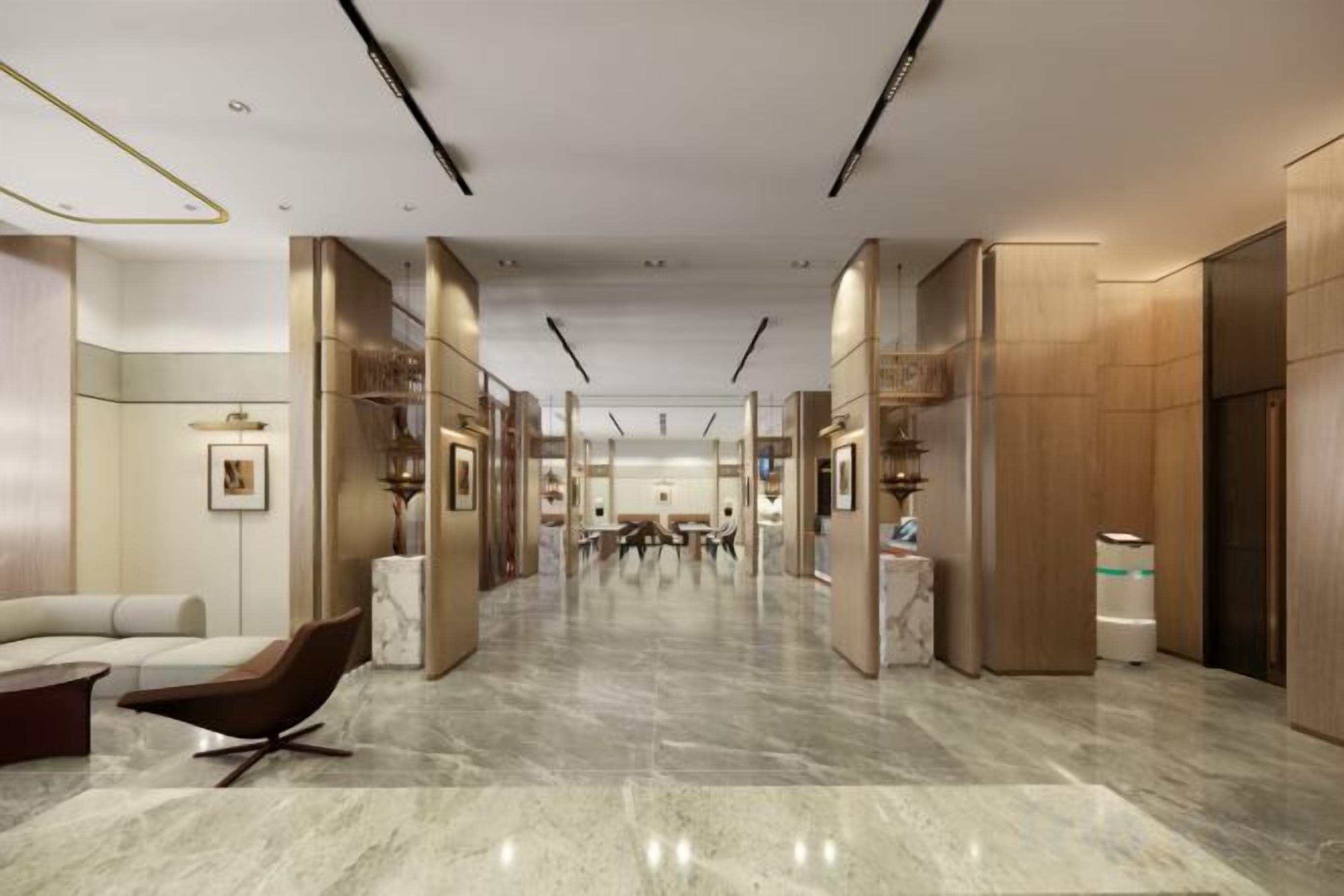 Eine geräumige Lobby mit Marmorboden, einer Rezeption und einer Sitzecke mit einem modernen Sessel.