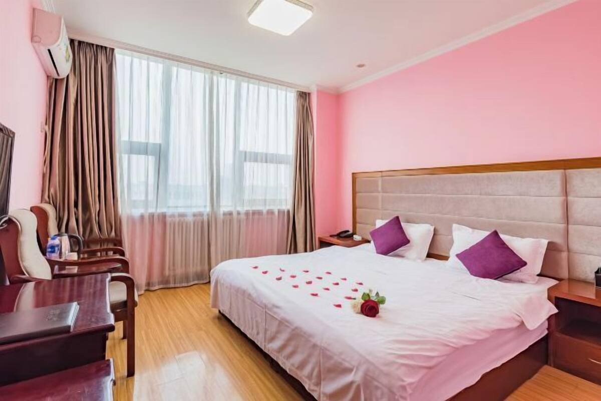 A hotel room with a large bed, a desk, and a chair.