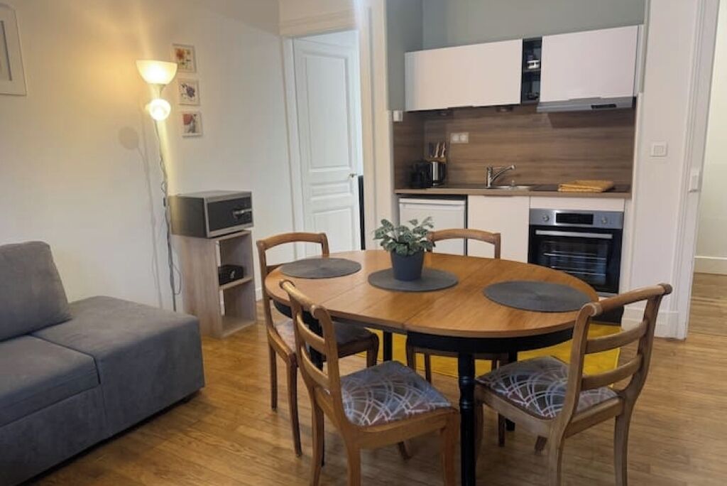 A compact living space with a dining area, kitchenette, and a gray sofa.