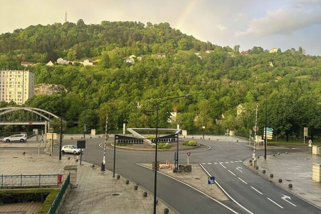 A multi-lane road with a pedestrian crossing and a roundabout.