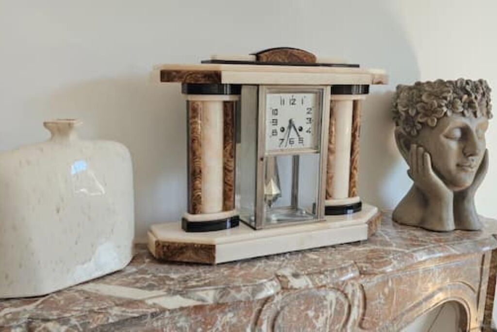 Une table en marbre ornée d’une horloge et d’un buste sculpté.
