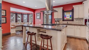Una cocina amplia con una isla central, muebles blancos y una pared de acento roja.